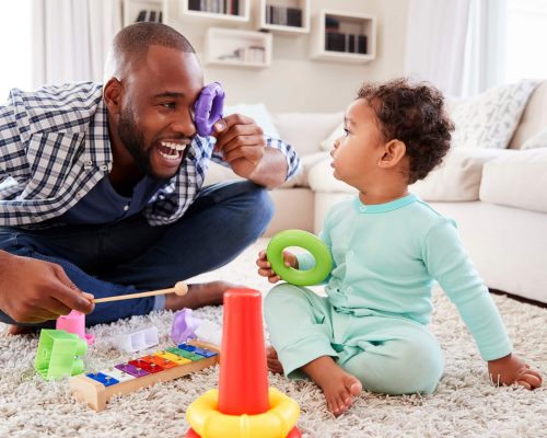 Dad and toddler son having fun playing at home, close up